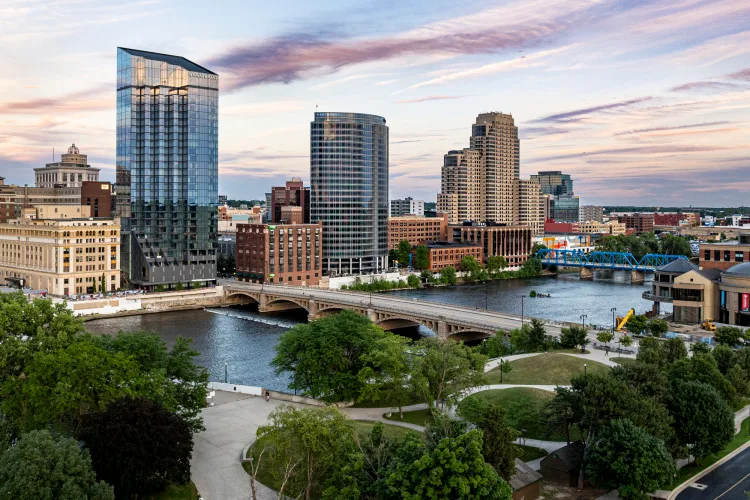 Grand Rapids, MI skyline with high-rise towers beside the Grand River and a riverside park